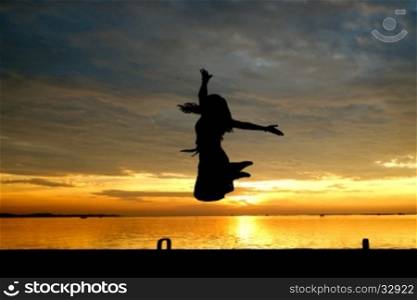 silhouette of woman jumping at the sea with beautiful sunset background
