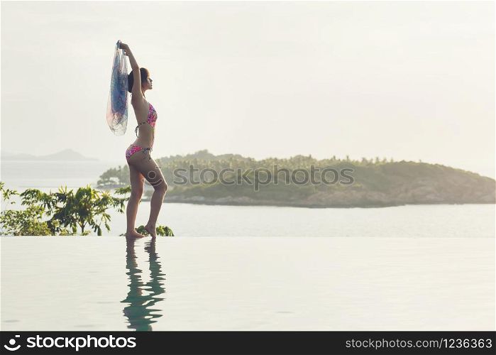 silhouette of woman posing on summer beach holiday relaxing in luxury spa hotel in infinity swimming pool with blue sea island view. Healthy lifestyle, fashion female travel background.