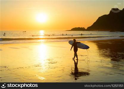 Silhouette of woman surfer walking to the ocean by sandy beach, Sagres, Algarve, Portugal