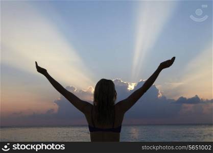 Silhouette Of Woman With Outstretched Arms On Beach