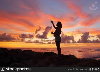 silhouette of women taking pictures on the beach beautiful sky background