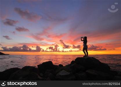 silhouette of women taking pictures on the beach beautiful sky background