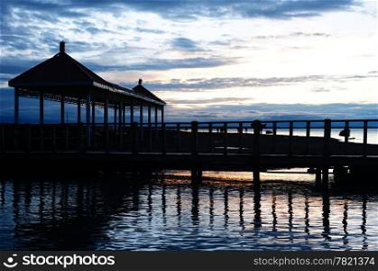 Silhouette of wooden pavilion and bridge at lakeside at sunset