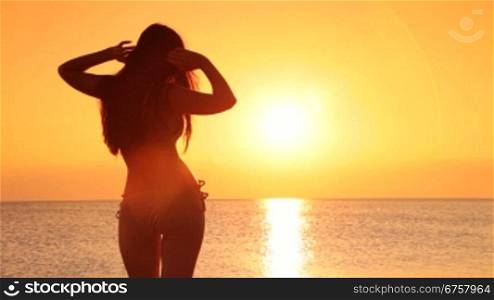 silhouette of young girl in a bikini at sunset