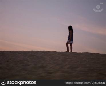 Silhouette of young girl on beach at sunset