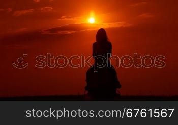 Silhouette of young girl riding horse at sunset