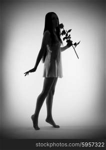 Silhouette of young girl with rose flower on gray background (black and white)