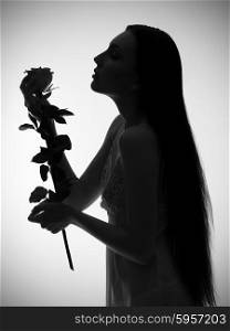 Silhouette of young girl with rose flower on grey background (monochrome version)