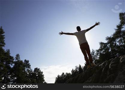Silhouette Of Young Man Standing On Rock