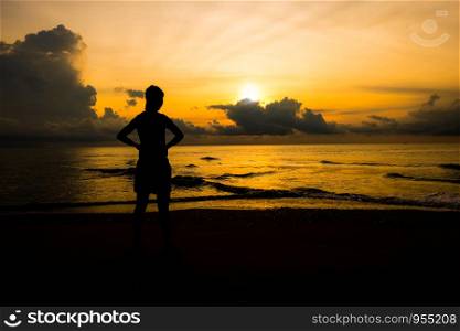 Silhouette of young sport women looking up sunrise or sunset at the beach that meaning the power of life and positive thinking.