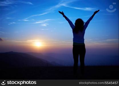 Silhouette of young woman against sunset with blue sky