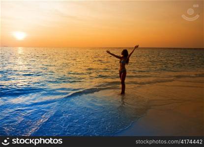 Silhouette of young woman in ocean towards sunset.