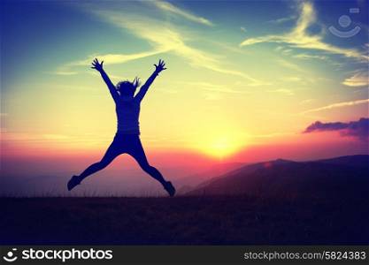 Silhouette of young woman jumping against sunset with blue sky. Colorized like instagram