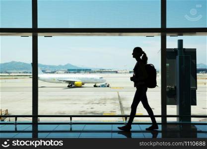 Silhouette of young woman walking at airport