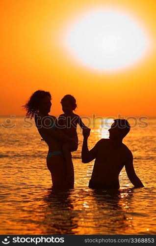 silhouette Parents with child in sea on sunset