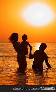 silhouette Parents with child in sea on sunset