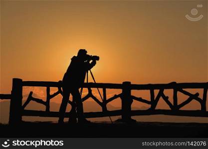 silhouette photographer is taking a photo with sunset