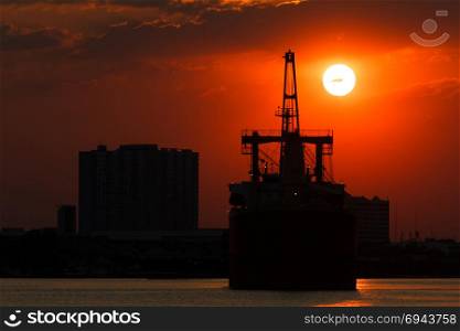 Silhouette picture of vessel with sunset in background.