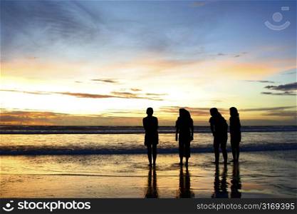 Silhouette shots of four girls on the beach enjoying the dramatic sunset