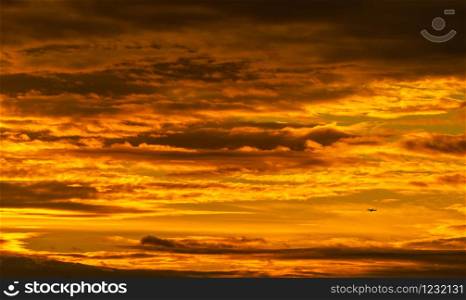 Silhouette small airplane flying on beautiful sunset sky. Golden vast sunset sky. Freedom and calm background. Beauty in nature. Powerful and spiritual scene. Dramatic and majestic golden sky.