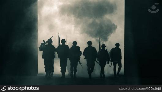silhouette Thailand soldiers special forces team full uniform walking action through smoke and holding gun on hand and over the lighting background