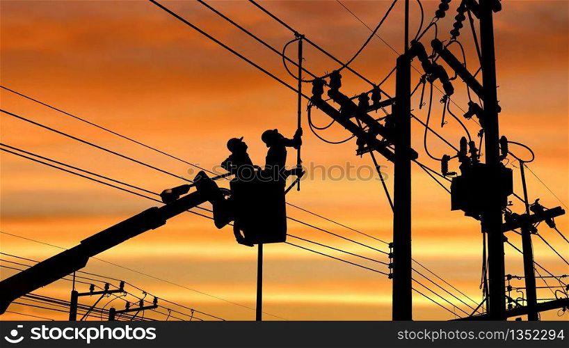Silhouette two electricians with disconnect stick tool on crane truck are working to install electrical transmission on power pole with blurred colorful sunrise sky background, illustration mode