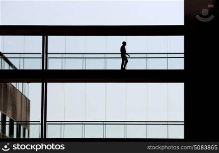 Silhouette view of a businessman in a modern office building interior with panoramic windows.