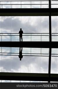 Silhouette view of a businessman in a modern office building interior with panoramic windows.. modern office man