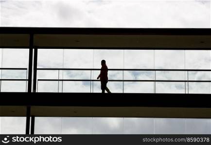Silhouette view of a businessman in a modern office building interior with panoramic windows.