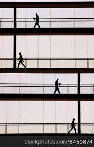 Silhouette view of businessmen in a modern office building interior with panoramic windows.