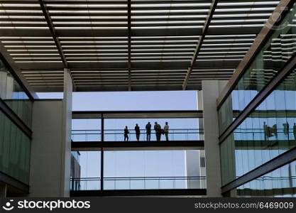 Silhouette view of some people in a modern office building interior with panoramic windows.