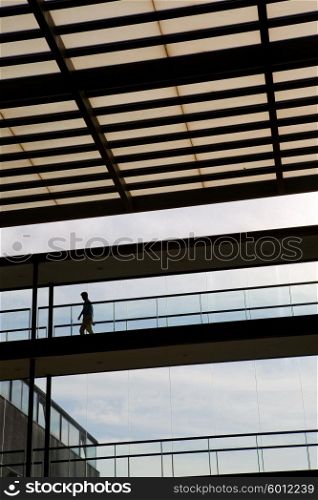 Silhouette view of young businessman in a modern office building interior with big windows.