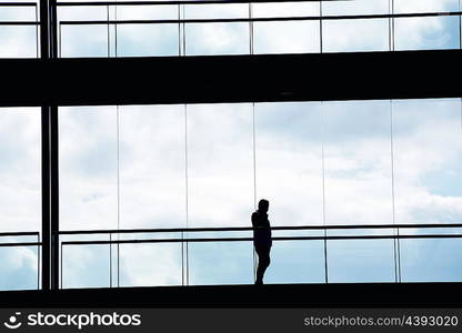 Silhouette view of young businessman in a modern office building interior with panoramic windows.