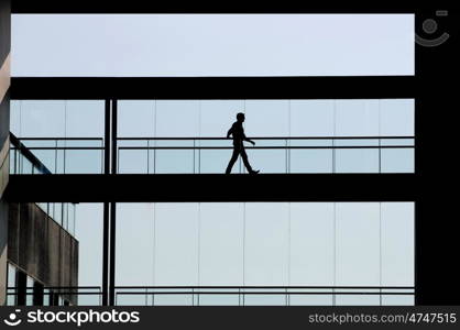 Silhouette view of young businessman in a modern office building interior with panoramic windows.