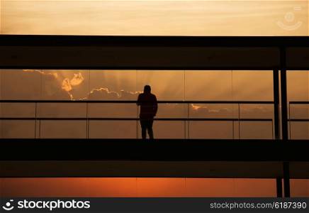 Silhouette view of young businessman in a modern office building interior with panoramic windows.