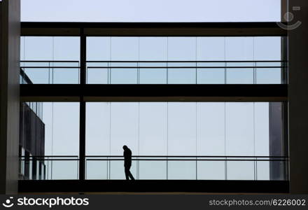 Silhouette view of young businessman in a modern office building interior with panoramic windows.