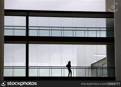 Silhouette view of young businesswoman in a modern office building interior with panoramic windows.