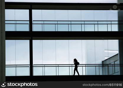 Silhouette view of young businesswoman in a modern office building interior with panoramic windows.. office woman