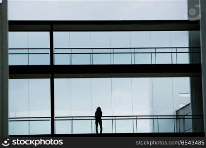 Silhouette view of young businesswoman in a modern office building interior with panoramic windows.. office woman