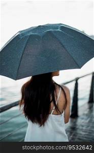 Silhouette  woman holding umbrella in the rain at sea, selective focus . Silhouette  woman holding umbrella in the rain at sea