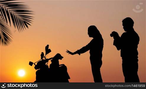 Silhouette young Asian couple are relaxing with taking picture of our pets on motorcycle at sea viewpoint in sunset time, lifestyle and spending time with the people we love concept