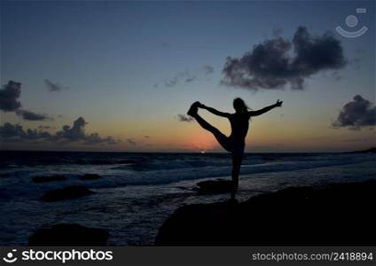 Silhouetted balance toe bind pose at sunrise in Aruba.