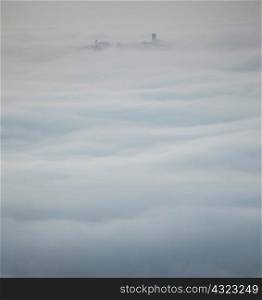 Silhouetted rooftops emerging from low cloud, Langhe, Piedmont. Italy