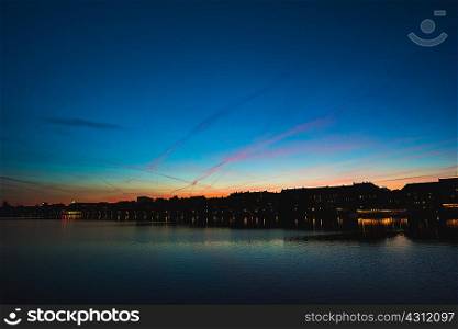 Silhouetted sunset over river waterfront, Copenhagen, Denmark