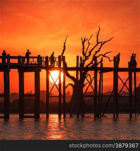 Silhouettes at U Bein teak bridge. local people and tourists enjoying sunset at Amarapura. Myanmar (Burma) travel landscapes and destinations