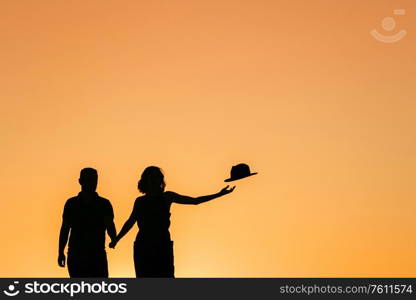 silhouettes of a happy young couple guy and girl on a background of orange sunset in the sand desert