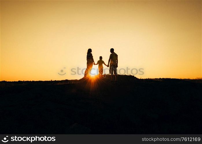 silhouettes of a happy young happy family against an orange sunset in the desert