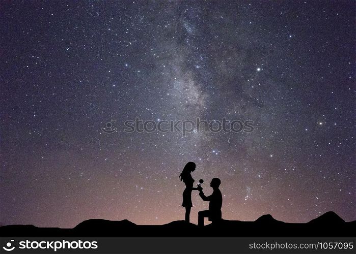 Silhouettes of a man making marriage proposal to his girlfriend on milky way, Landscape with silhouette of lovers