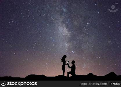 Silhouettes of a man making marriage proposal to his girlfriend on milky way, Landscape with silhouette of lovers