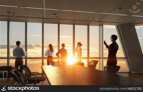 Silhouettes of Business People in Office. Mixed media. Group of business people working in office in lights of sunset